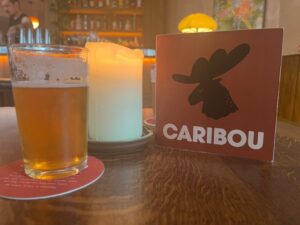 A glass of beer, a candle and a cocktail menu at Caribou